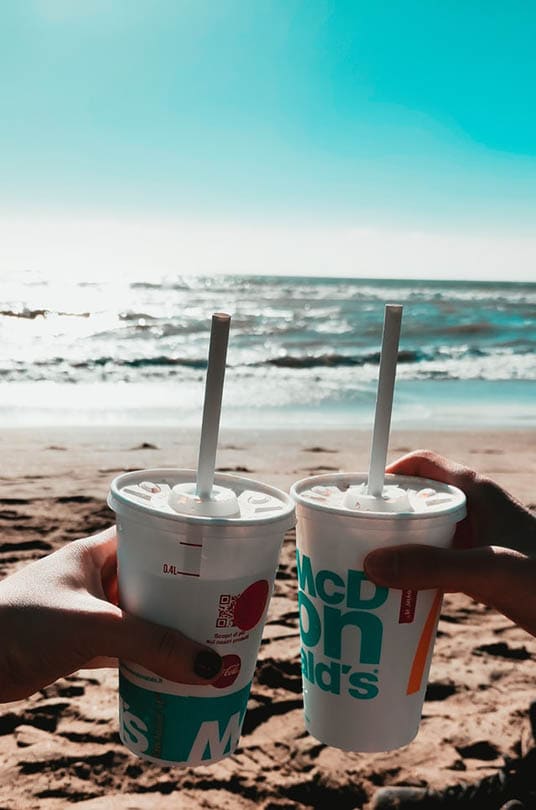 两个人在海滩上拿着麦当劳的饮料