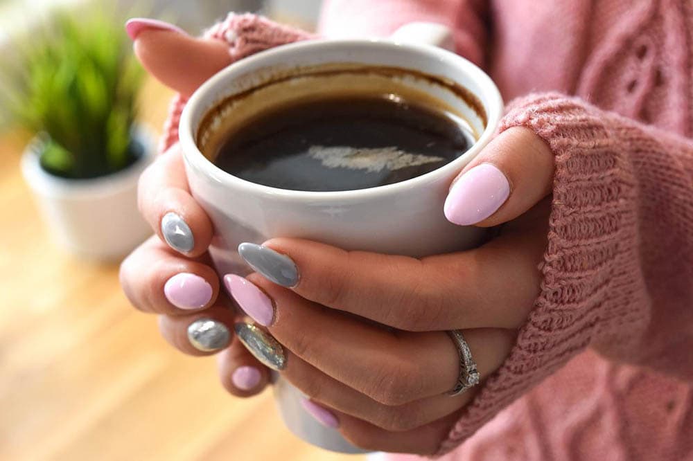 指甲擦亮的女人正在喝咖啡