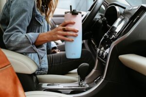 女人拿着简易现代旅行咖啡杯在车里